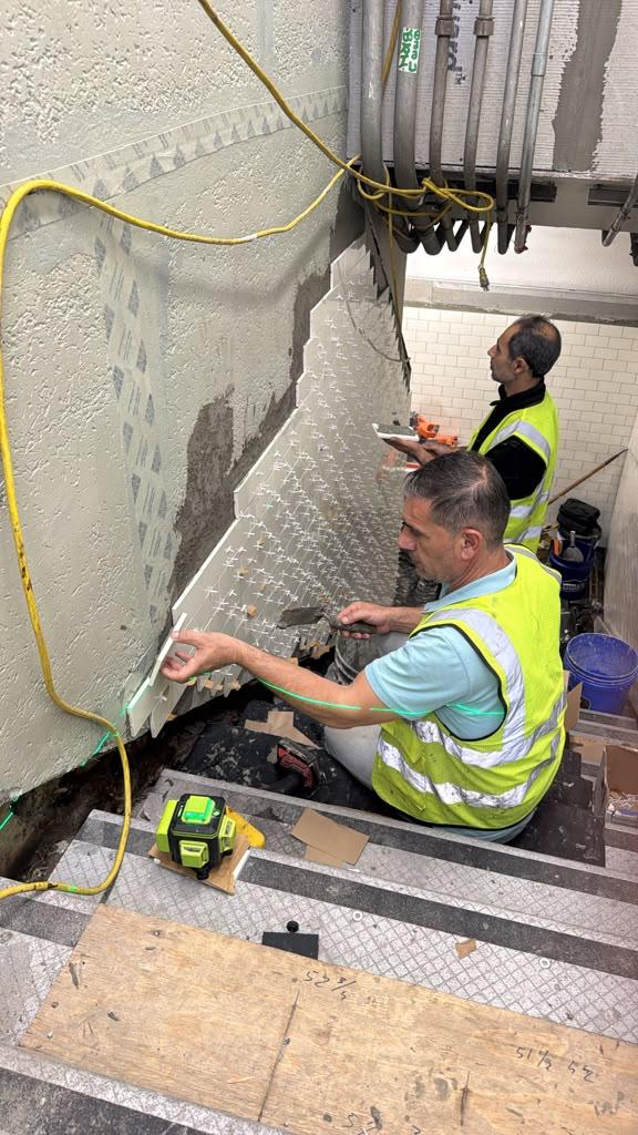 MJ Stone and Tile crew installing stair wall tile at Newport PATH Station